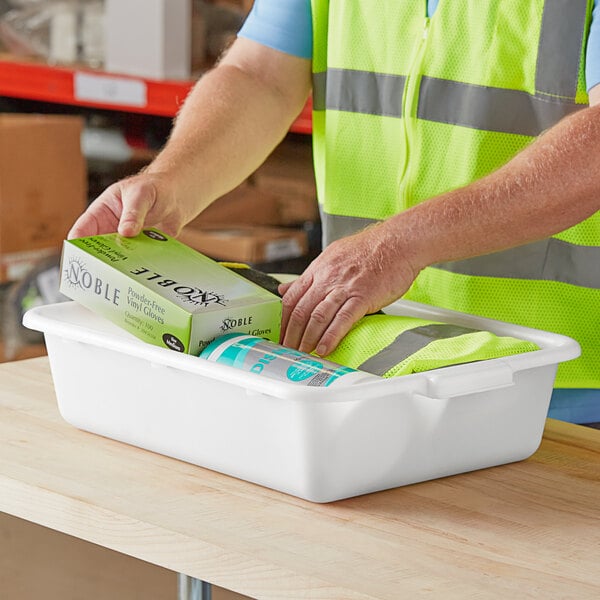 A man in a safety vest putting a box in a white Lavex utility bin.