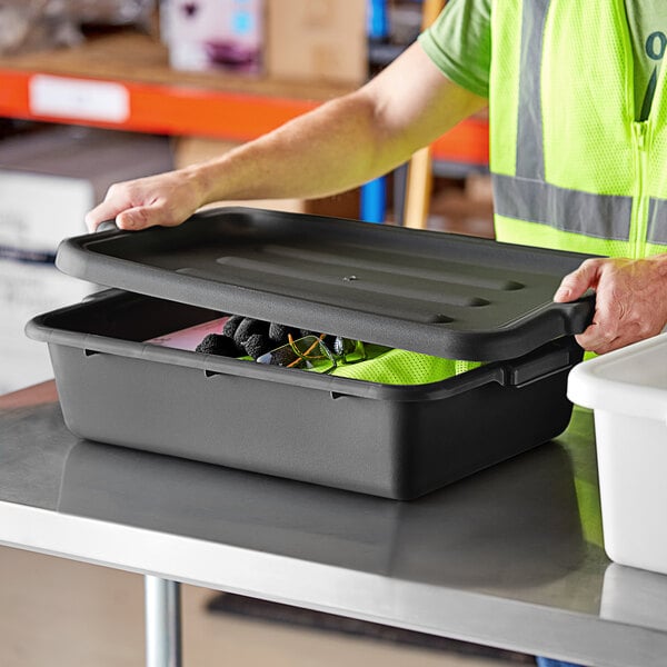 A man in a safety vest opening a black Lavex polypropylene utility bin on a table.