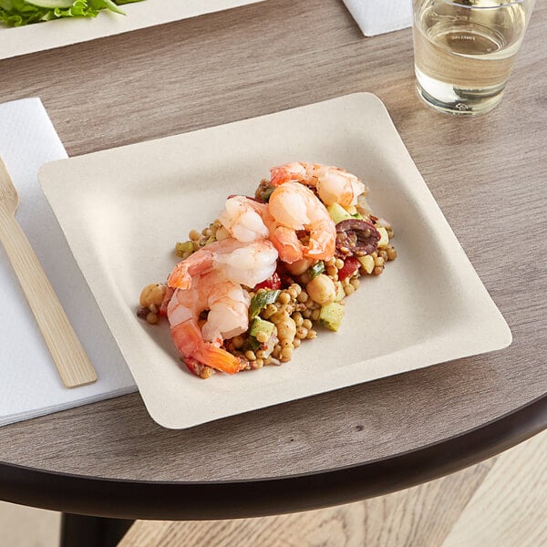 A World Centric compostable fiber plate with shrimp and vegetables on it on a table.