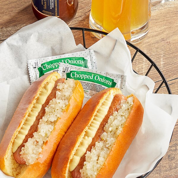 A plate with two hot dogs with mustard and ketchup, a basket of hot dogs, and a drink on a table at a stadium concession stand.