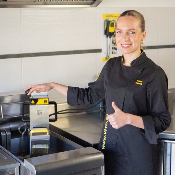 A woman in a black uniform using a VITO fryer oil filter machine.