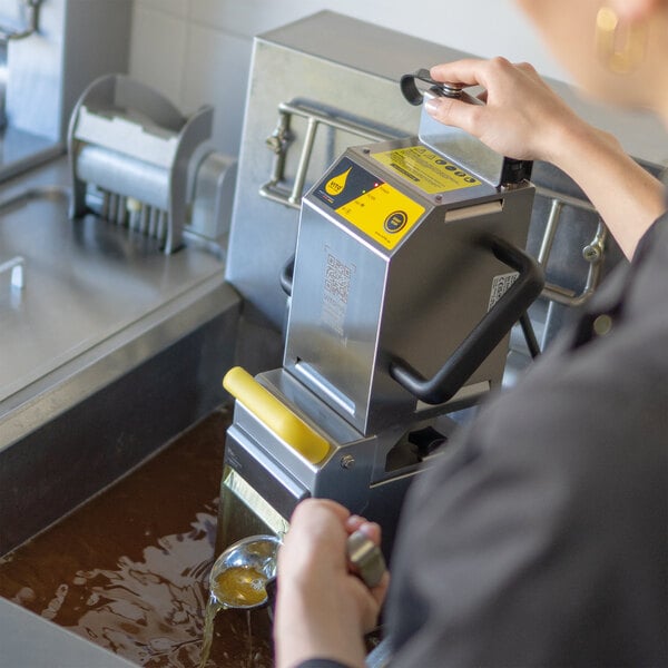 A person using a VITO fryer oil filtration machine on a counter.