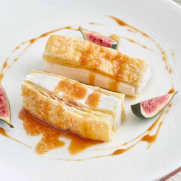 A white plate topped with two pastries with figs and a fig slice on the side.