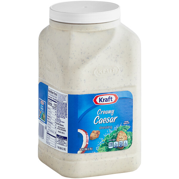 A white plastic container of Kraft Creamy Caesar Dressing with a blue label.