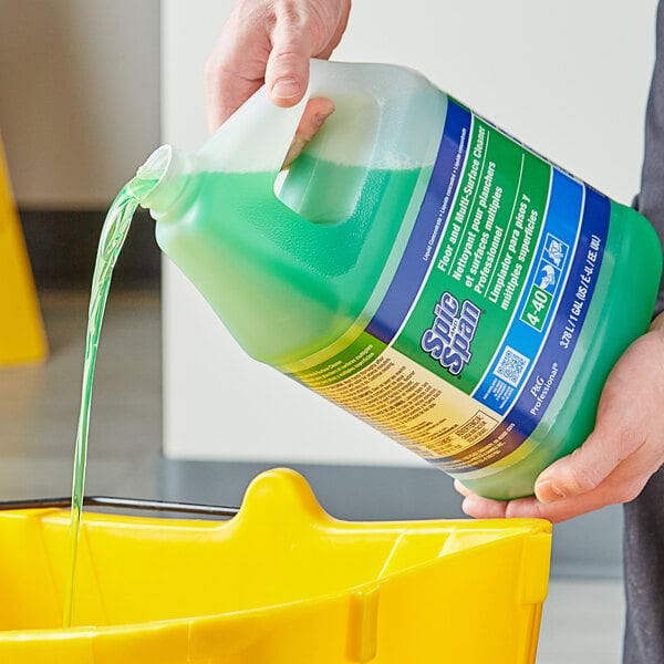 A person pouring Spic and Span floor cleaner into a yellow container.