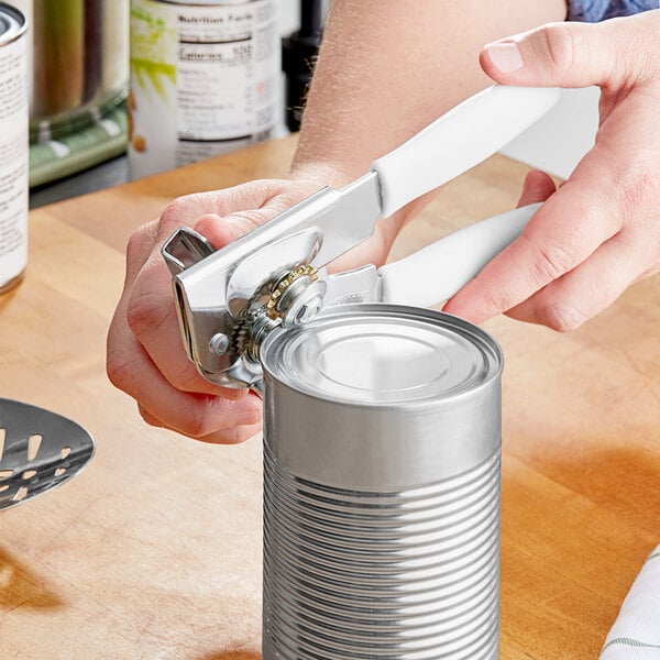 A person using a Swing-A-Way handheld can opener with a white handle to open a can.