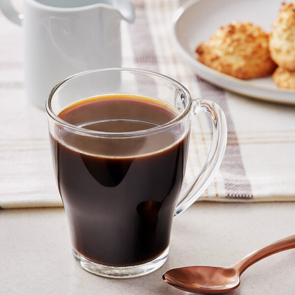 A glass cup of Ellis Bag in Box Bold Decaf Coffee next to a plate of cookies.