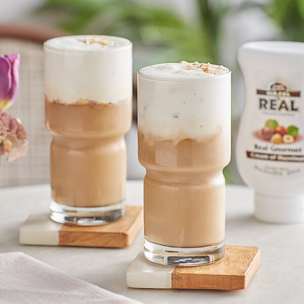 Two glasses of coffee with Real Cream of Hazelnut Infused Syrup in them on a table.