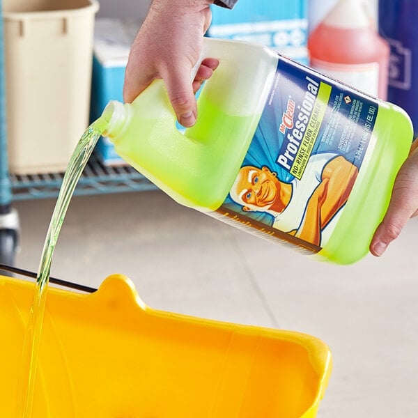 A person pouring green Mr. Clean floor cleaner into a yellow bucket.