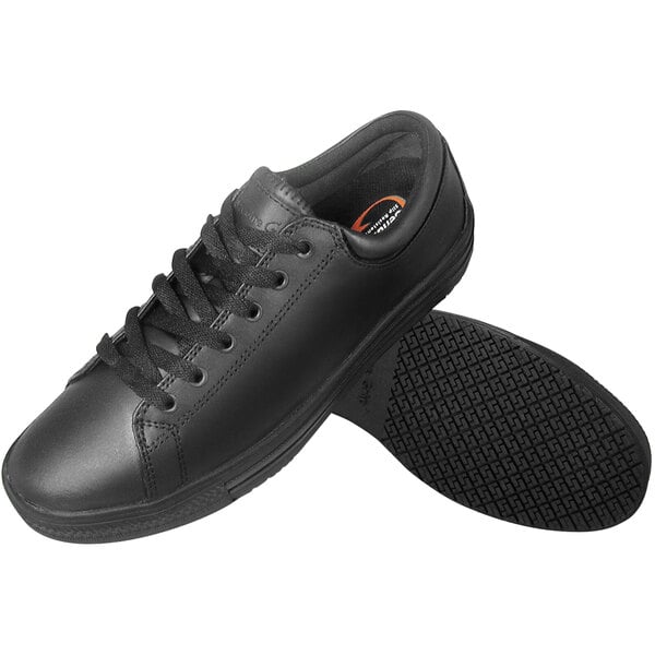 A close-up of a black Genuine Grip men's shoe with laces and an orange sole.