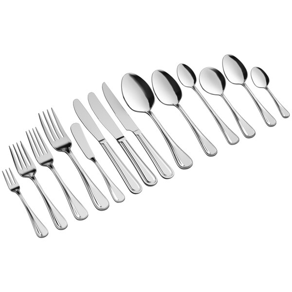 An Acopa Lydia stainless steel steak knife and several spoons.