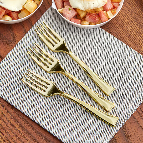 A Visions gold plastic tasting fork on a table with breakfast food.