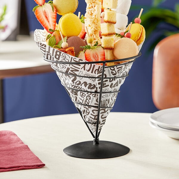 A black metal cone shaped fruit basket filled with yellow food.