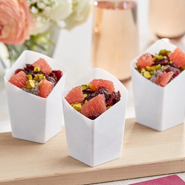 A group of small white Choice plastic containers filled with fruit.