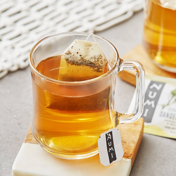 A glass mug of Numi Organic Dandelion Detox tea with a tea bag in it.