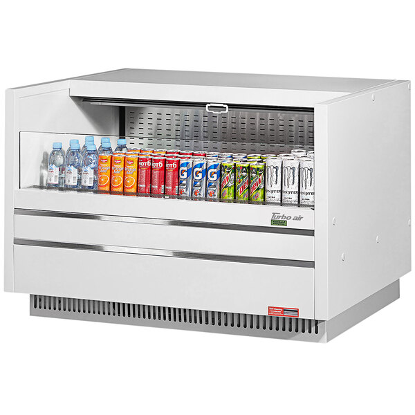 A white Turbo Air drop-in refrigerated display case with cans of soda and water.