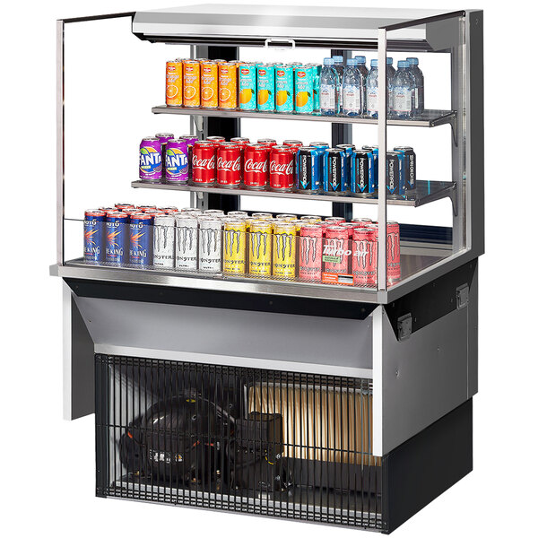 A Turbo Air drop-in refrigerated display case with cans of soda and water on shelves.