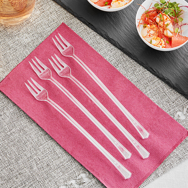 A group of Visions clear plastic tasting forks on a pink napkin.