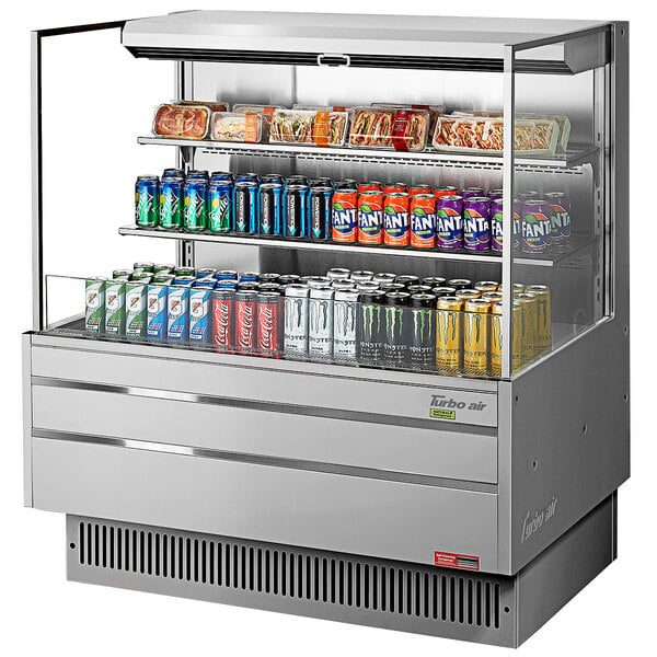 A Turbo Air stainless steel horizontal refrigerated open curtain merchandiser with shelves filled with cans of soda.