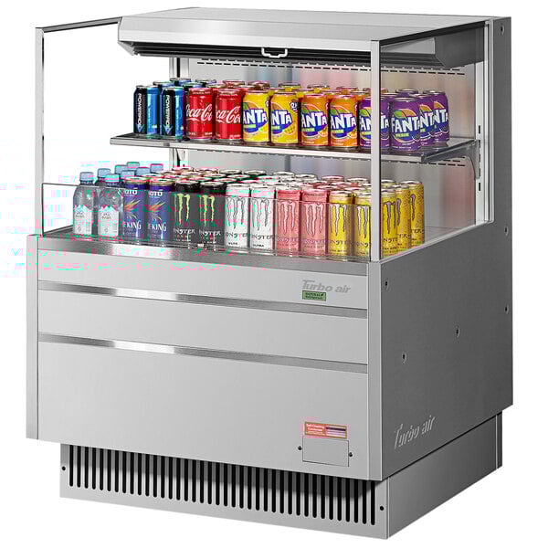 A Turbo Air stainless steel horizontal refrigerated open curtain merchandiser with drinks on a shelf.