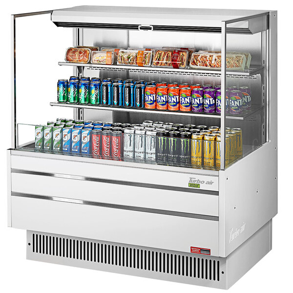 A white Turbo Air horizontal refrigerated open curtain merchandiser with drinks and cans on shelves.