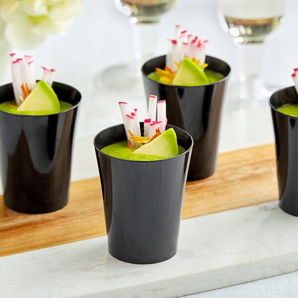 A tray of black Choice plastic shot glasses filled with green liquid.