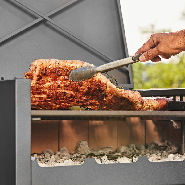 A person cooking meat on a Nuke BBQ Delta grill.