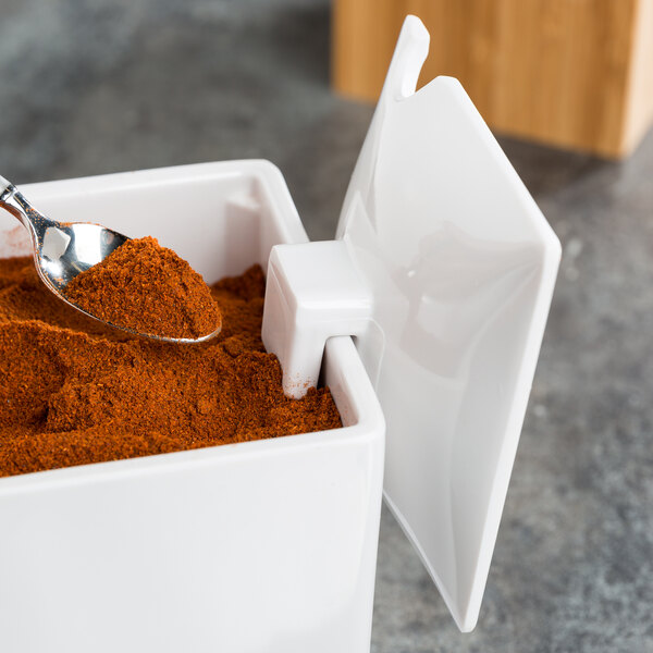 A Cal-Mil white melamine notched lid with a spoonful of red powder.