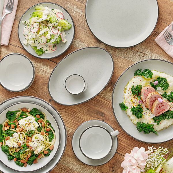 A wood table with Acopa grey matte stoneware platters of food.