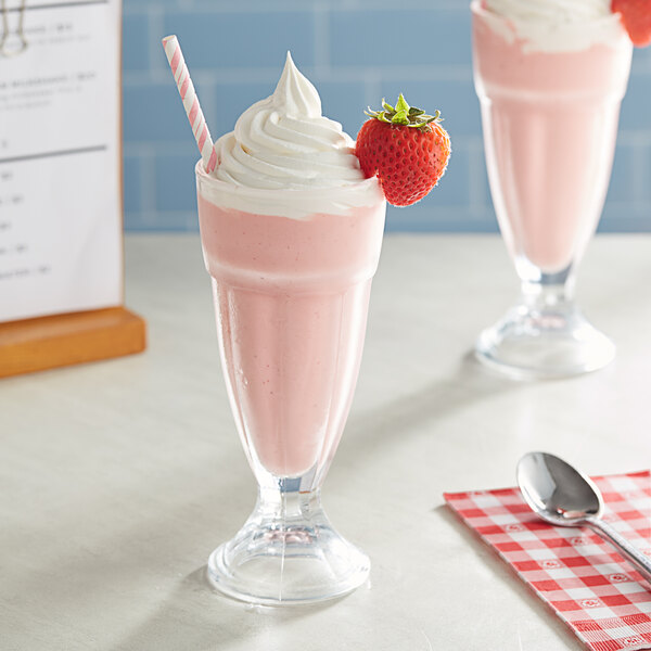 Two glasses of pink milkshakes with straws and a strawberry on top.