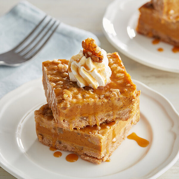 A close up of a caramel dessert with whipped cream on a plate.