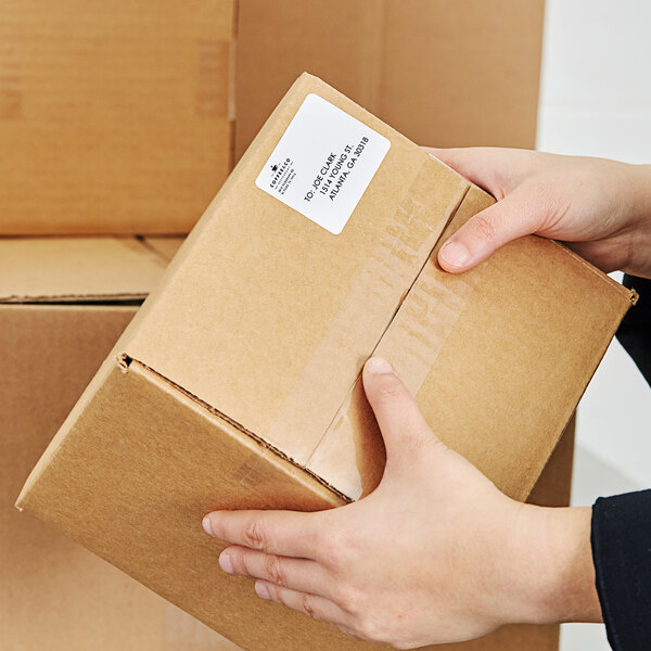 A person holding a box of AvaWeigh white blank labels.