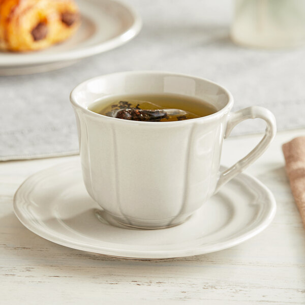 An Acopa Condesa warm gray porcelain cup of tea on a saucer.