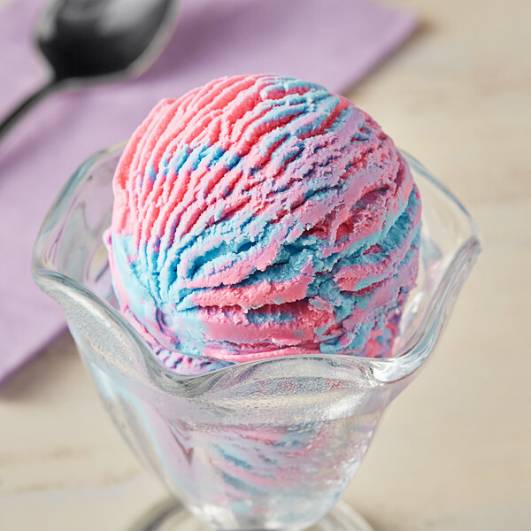 A scoop of Oringer Cotton Candy hard serve ice cream in a clear bowl with blue and pink swirls.