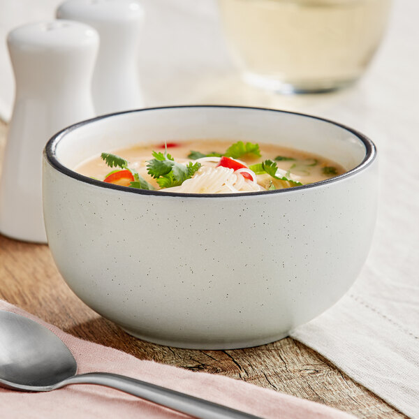 An Acopa Embers stoneware bowl filled with soup and noodles on a white surface.