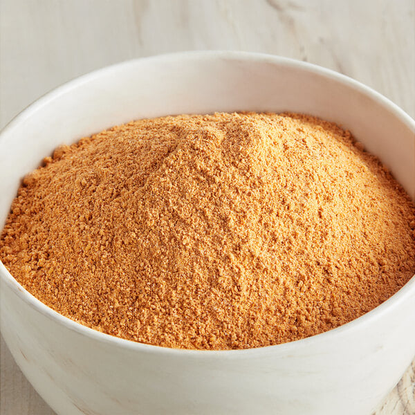 A bowl of McCormick Culinary Mesquite Barbecue Seasoning powder on a wooden table.