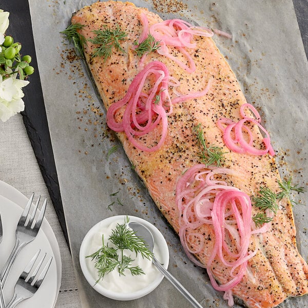 A fish fillet with McCormick Culinary Lemon and Pepper Seasoning Salt and onions on top with a bowl of cream sauce.