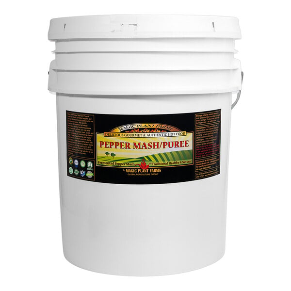 A large white plastic bucket with a black label indicating it contains pepper mash or puree.
