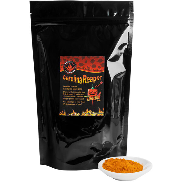 A black bag with a red label of Fiery Farms Red Carolina Reaper Pepper Powder next to a bowl of chili.