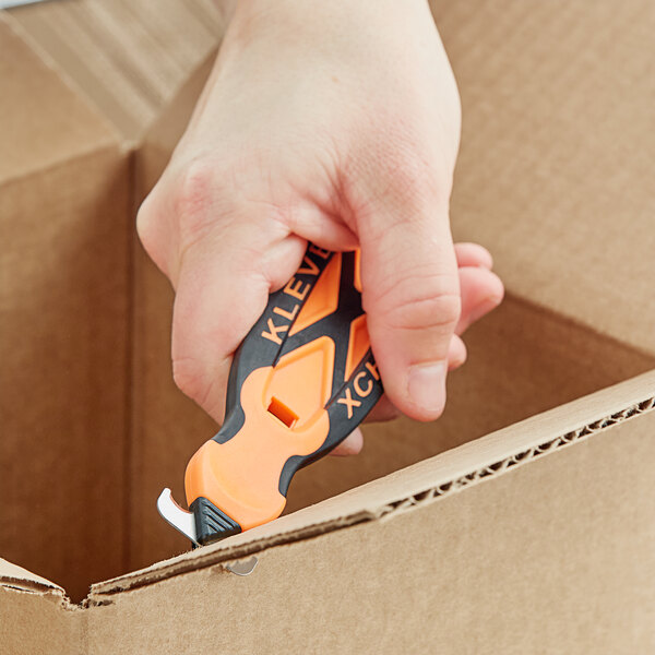 A person's hand using a Klever Kutter X-Change box cutter with a Kurve head.
