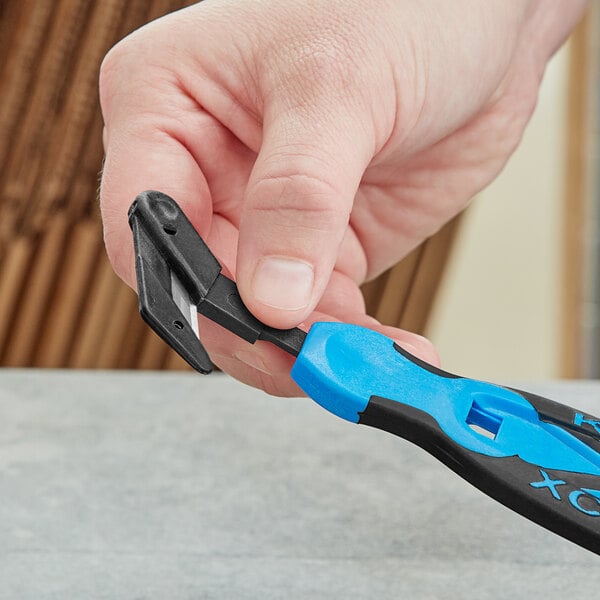 A hand holding a black and blue Klever X-Change Wide Head Blade tool.