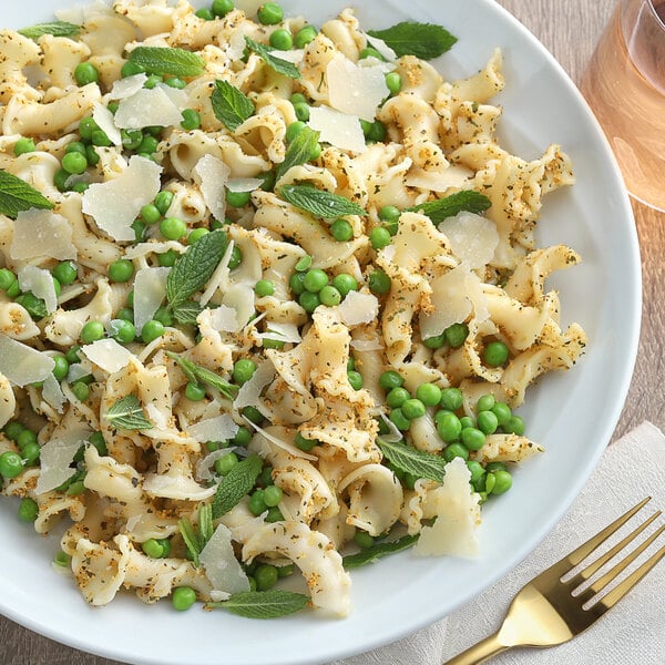 A white plate of pasta with peas and parmesan cheese seasoned with McCormick Perfect Pinch Salt-Free Garlic and Herb seasoning.