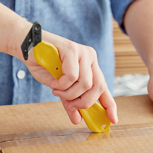 A person using a Klever Kutter Excel yellow box cutter to open a box.