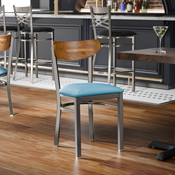 A metal chair with a blue vinyl seat and a curved wooden backrest.