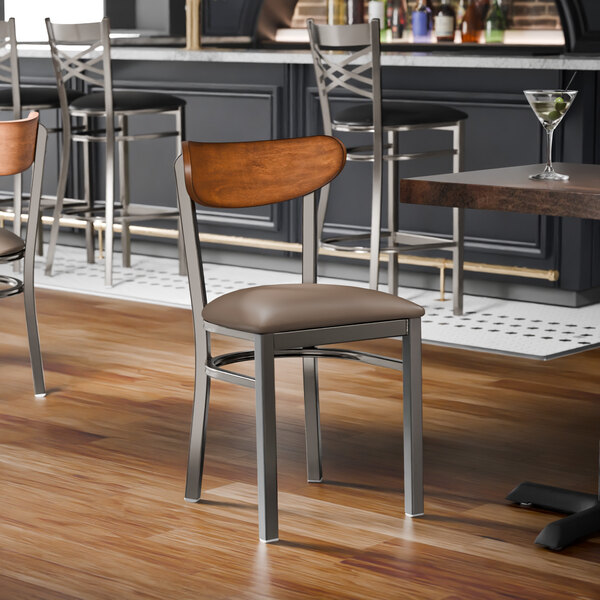 A metal chair with a taupe vinyl seat and an antique walnut wood backrest.