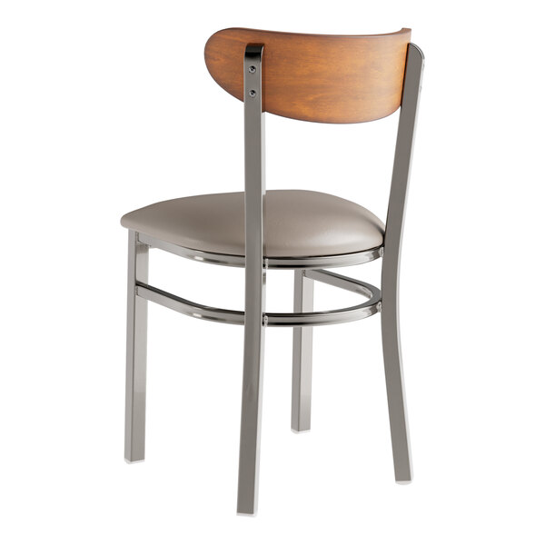 A Lancaster Table & Seating Boomerang chair with a wood seat and back and a cushioned dark gray vinyl seat.