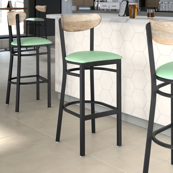 Three Lancaster Table & Seating black bar stools with seafoam vinyl seats.