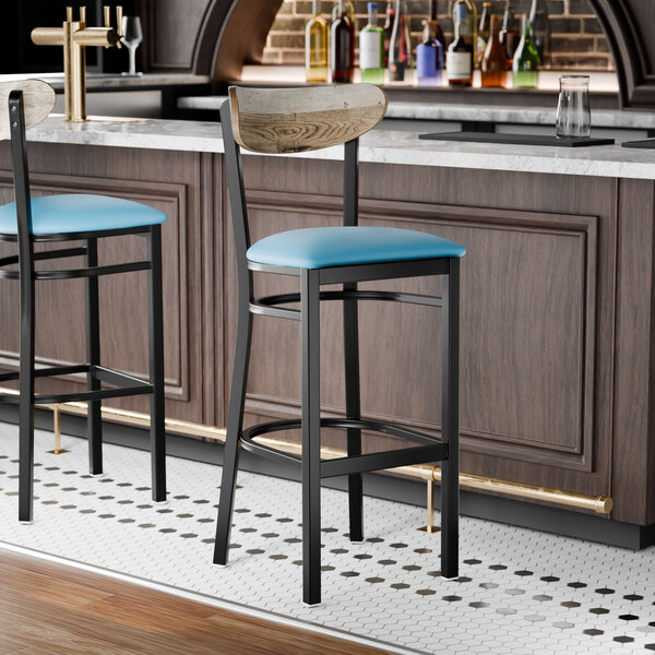 A black bar stool with a blue vinyl seat and a driftwood-finished wooden backrest.