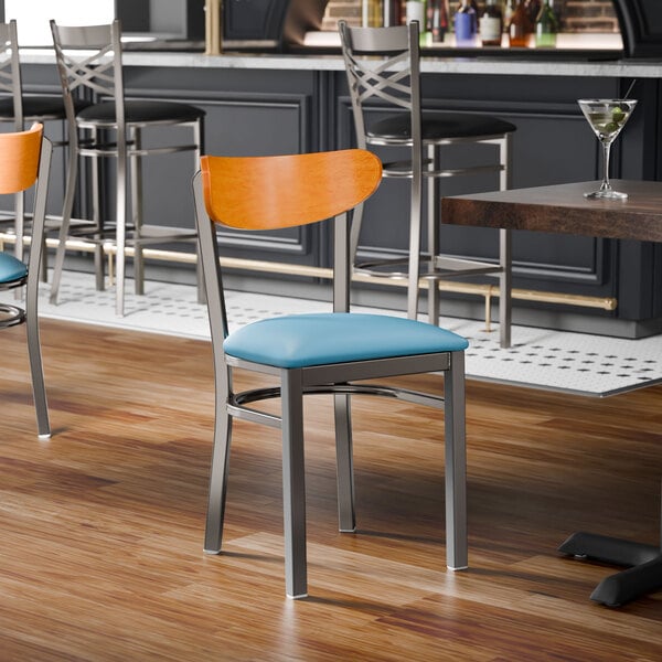 A metal chair with a blue vinyl seat and a cherry wood backrest.