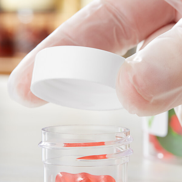 A person in gloves holding a white plastic 33/400 Continuous Thread flat lid.